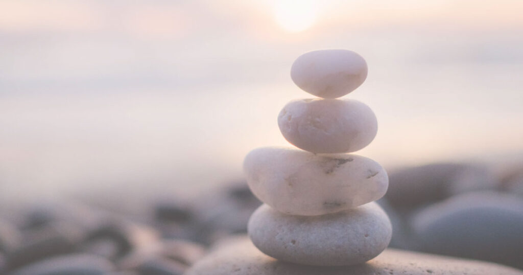 Some stacked pebbles in front of a lovely calming sunset